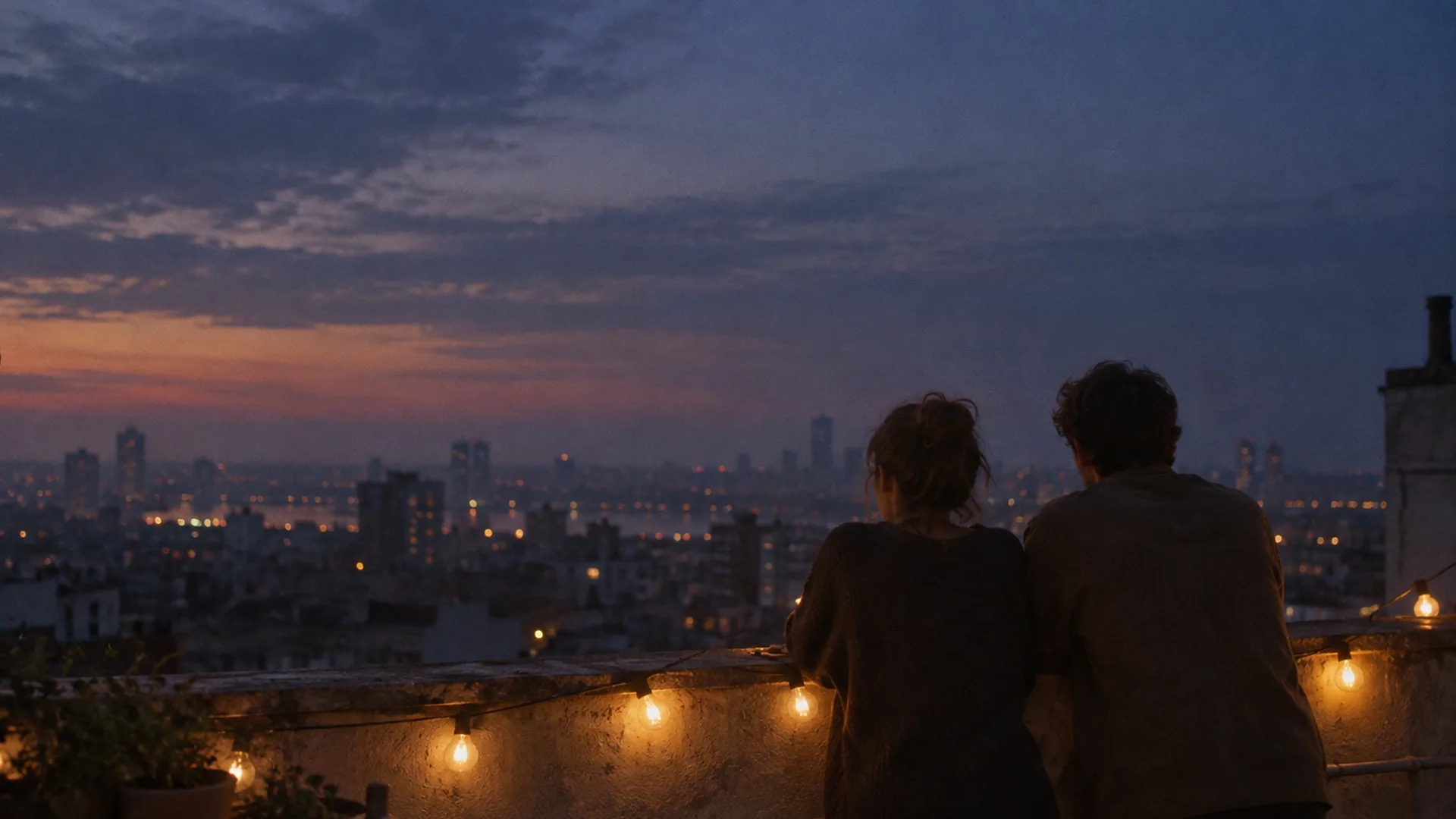 Rooftop at dusk with two figures at the parapet, warm string lights against a deep blue sky
